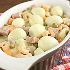 a casserole dish filled with meat and vegetables on a red and white checkered cloth