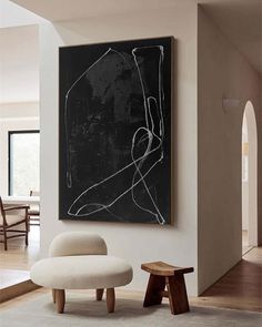 a black and white painting hangs on the wall above a chair in a living room