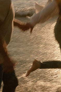 two people walking on the beach holding hands and touching each other's feet as they walk towards the water