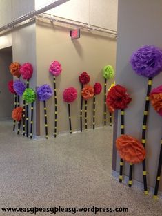 colorful paper flowers are placed on the wall next to each other in an office lobby