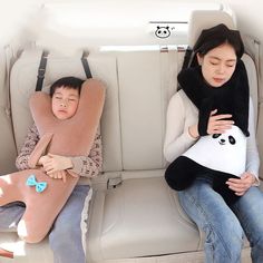 two people sitting in the back of a car with one holding a sleeping bag while the other sleeps