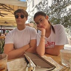 two people sitting at an outdoor table with drinks