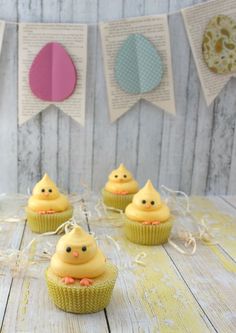 small cupcakes with yellow frosting sitting on top of a white wooden table