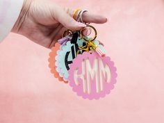 a hand holding a keychain with the word mm on it's side