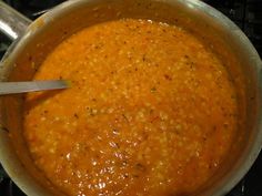 a pot filled with soup sitting on top of a stove next to a spatula