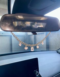 there is a gold chain attached to the rear view mirror in this car, with charms hanging from it's sides