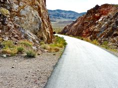 an empty road between two large rocks in the desert