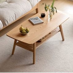 a coffee table with two pears on it in front of a couch and window