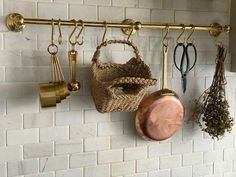 pots and pans are hanging on the wall next to each other with gold handles