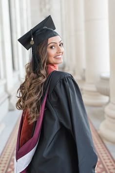 a woman wearing a graduation cap and gown standing in front of pillars with columns behind her