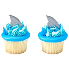 two cupcakes with blue frosting and a shark fin on each one side