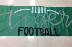 a green banner with the words tiger football written in silver ink on it's side