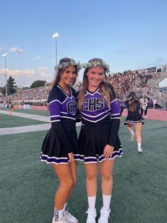 two cheerleaders posing for the camera at a football game