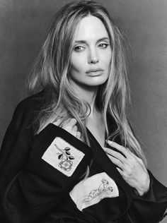 a black and white photo of a woman with long blonde hair wearing a jacket over her shoulders