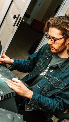 a man sitting down writing on a piece of paper