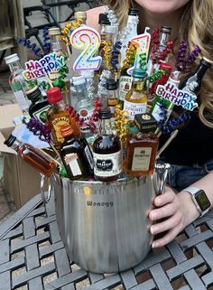 a woman is holding a bucket full of liquor and confetti for two birthdays