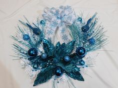 a blue and white christmas wreath with ornaments on it's side, sitting on a table