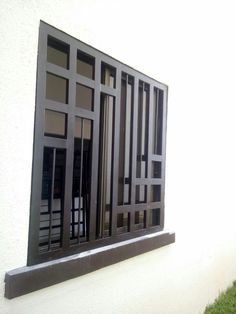 an open window on the side of a white building with black bars and grills