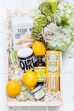 a basket filled with oranges, lemons and other items next to some flowers