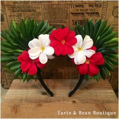 red and white flowers are on top of green leaves in the shape of a wreath