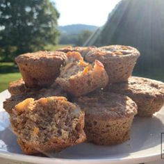 muffins stacked on top of each other on a white plate with trees in the background