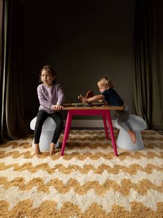 two children sitting at a table in front of curtains