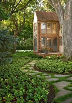 a small house surrounded by lush green trees and shrubbery in front of a tree