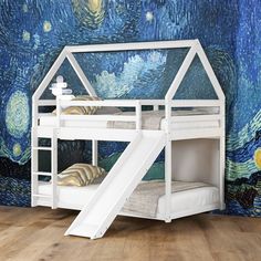 a white bunk bed with a slide in front of a starry night wall mural