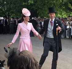 a man and woman dressed in pink walking down the street with people watching from behind them