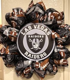 a wreath made out of footballs and the words las vegas raiders on it is hanging in front of a door