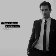 a man in a suit and tie standing next to a wall with a quote on it