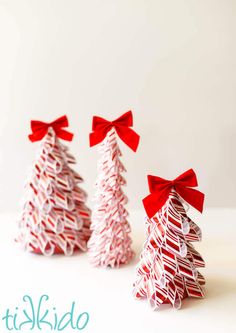 three small paper christmas trees with red bows on them, sitting next to each other