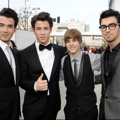 three young men in tuxedos are posing for a photo with one man giving the thumbs up