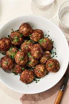 a white bowl filled with meatballs and garnished with parsley