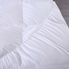 an unmade bed with white sheets and pillows on top of the bed, next to a wooden floor