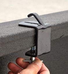 a hand is holding an object on the edge of a wall with a screwdriver attached to it