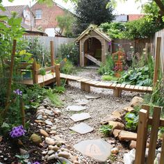 an outdoor garden with rocks, plants and a dog house in the backround