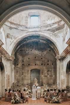 the bride and groom are standing at the alter in an old church, surrounded by chairs