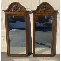 two large mirrors sitting next to each other on the side of a building in front of a garage door