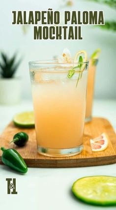 two glasses filled with orange juice and garnished with limes on a cutting board