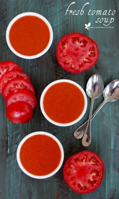 three bowls of tomato soup with spoons and tomatoes