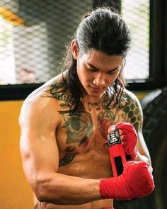 a man with long hair wearing red boxing gloves and holding a punching glove in his right hand