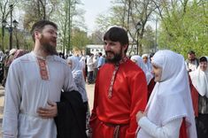 two men and a woman dressed in medieval garb talking to each other at an outdoor event