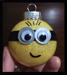 a hand holding a yellow ornament with googly eyes