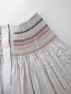 a white dress with multicolored lines on the front and back, hanging up against a wall