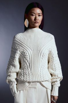 a woman in white sweater and pants posing for the camera