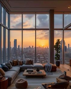 a living room filled with lots of furniture and large windows overlooking the city at sunset