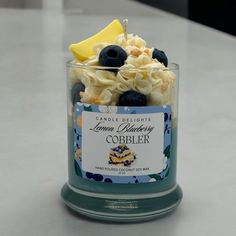 a jar filled with blueberries, lemon wedges and whipped cream on top of a table