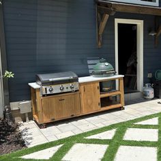 a bbq grill sitting on top of a wooden table next to a blue building