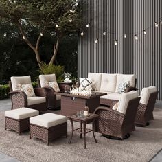 an outdoor living room with wicker furniture and lights on the side of the building